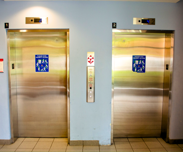 Two elevators side by side on a light blue wall