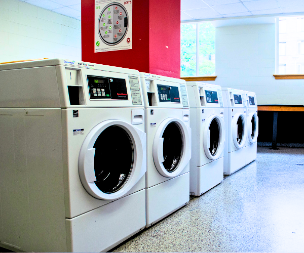 A row of laundry machines in a room with natural lighting