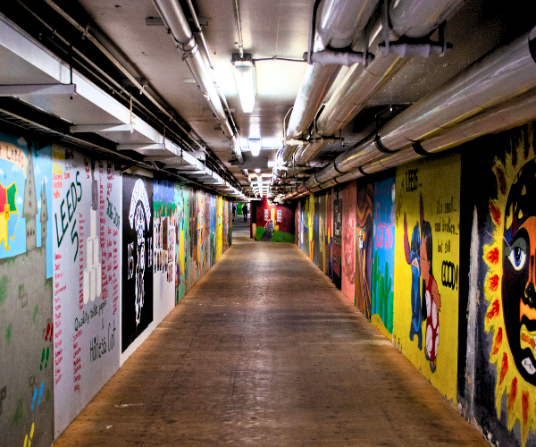 An underground tunnel hallway with colourful artwork on both walls