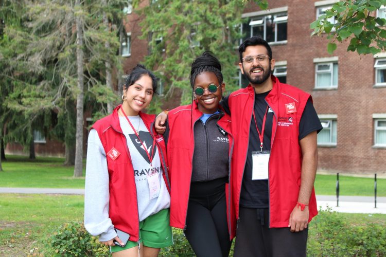 Three students smiling in red residence jackets