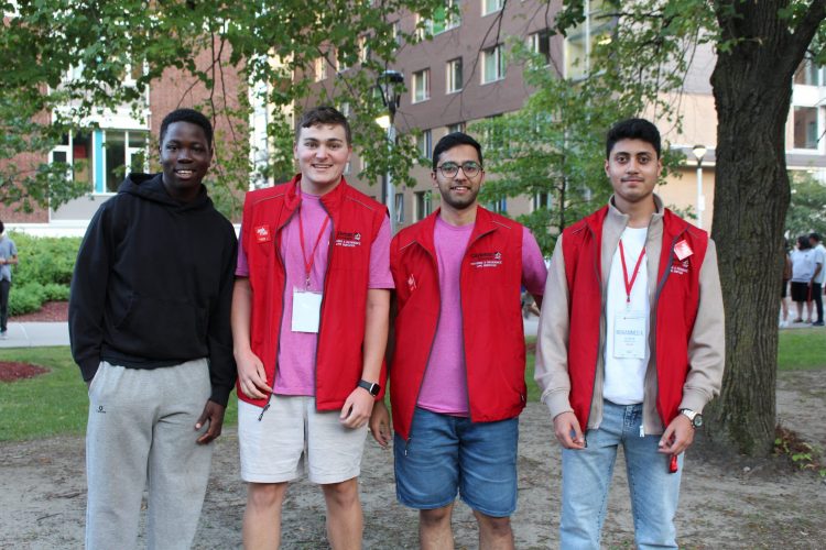 Four students wearing red residence jacket