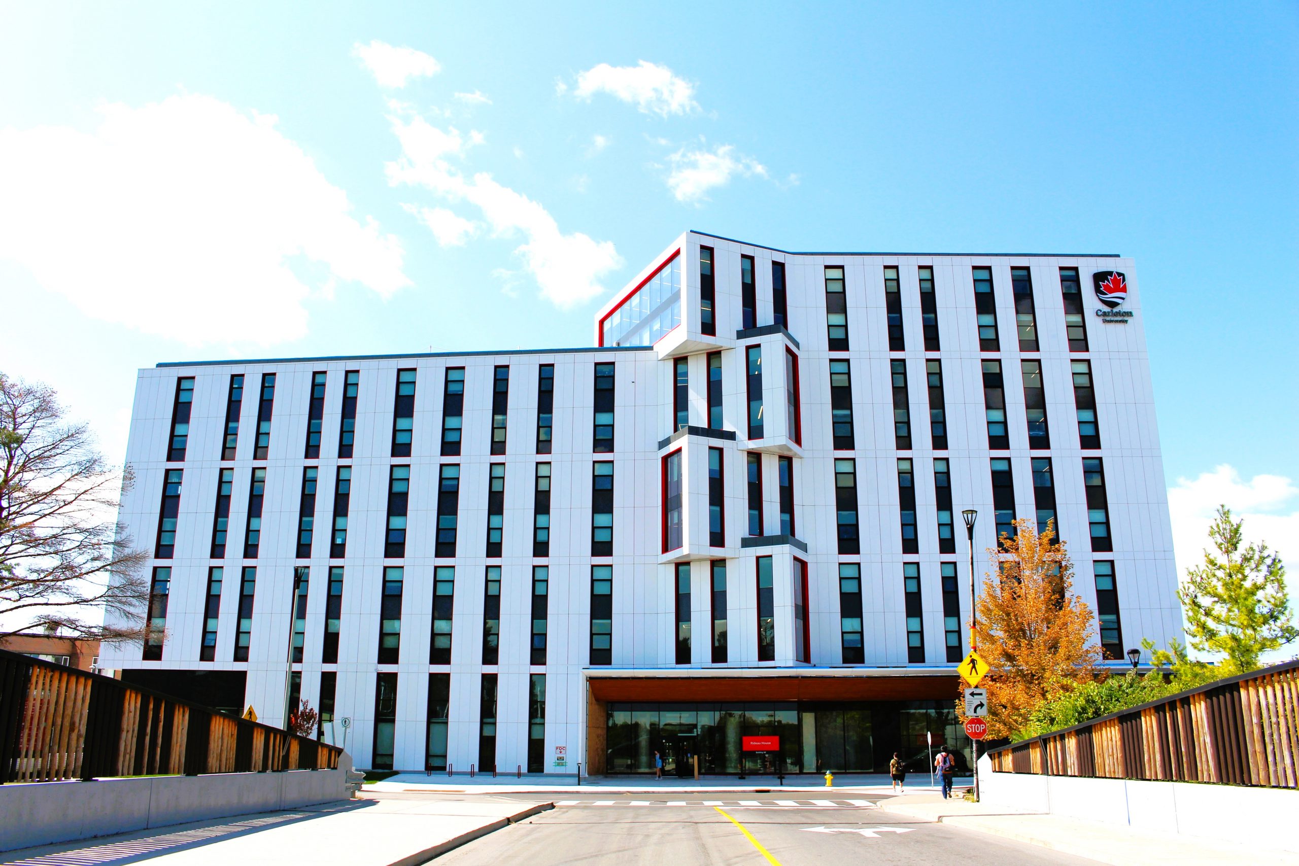 The exterior of Rideau House. A modern building with unique angular architecture, surrounded by snow-dusted trees and people.