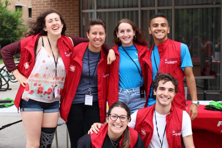 A group of residence helpers wearing red vests pose for a photo