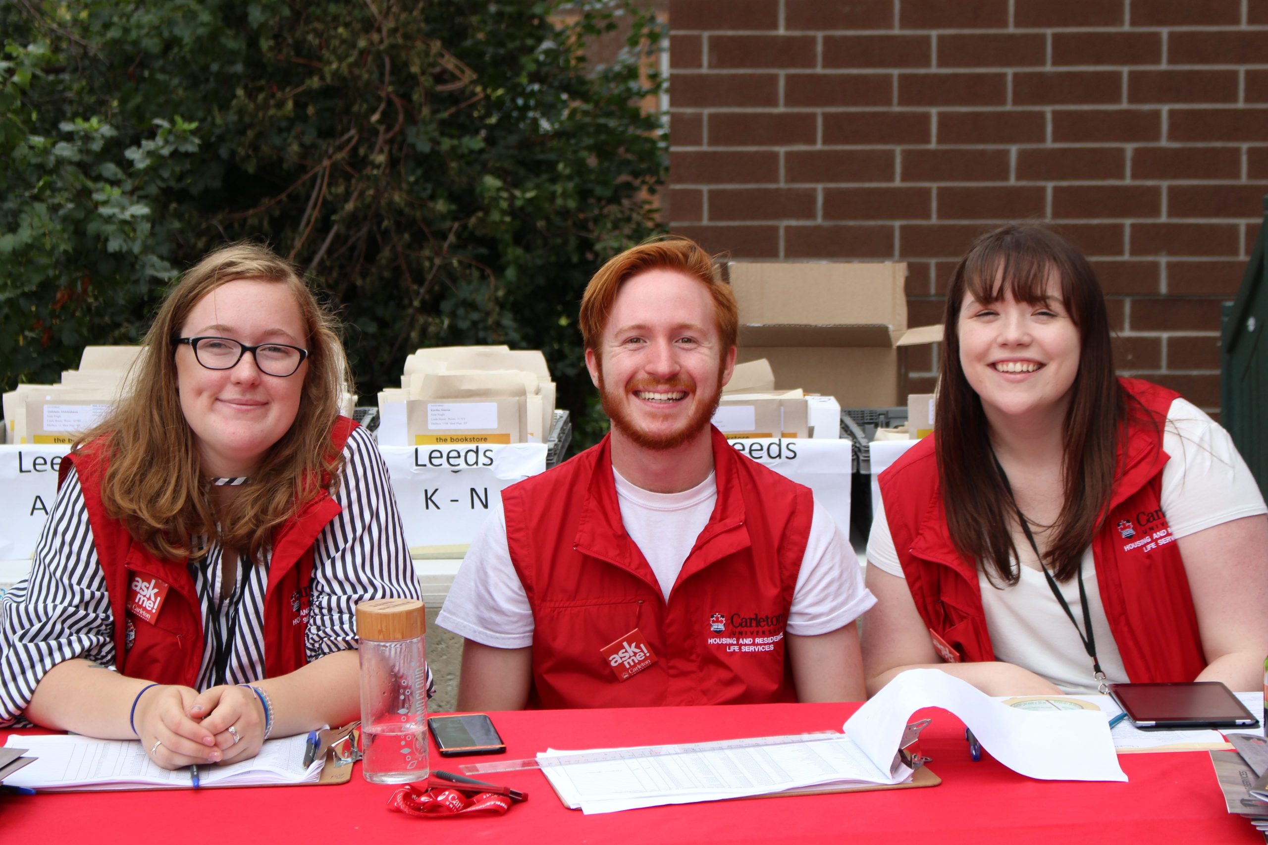 Three residence move-in helpers sit at a desk