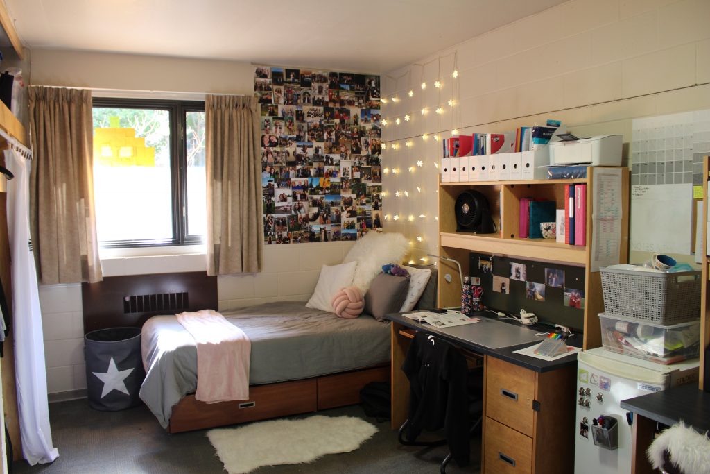 A decorated residence room with a bed, desks and a photo collage