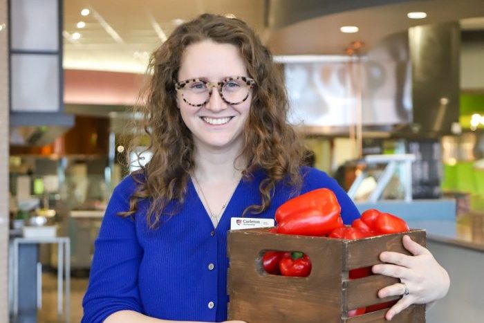 A woman holds a basket of red bell peppers at the caf.