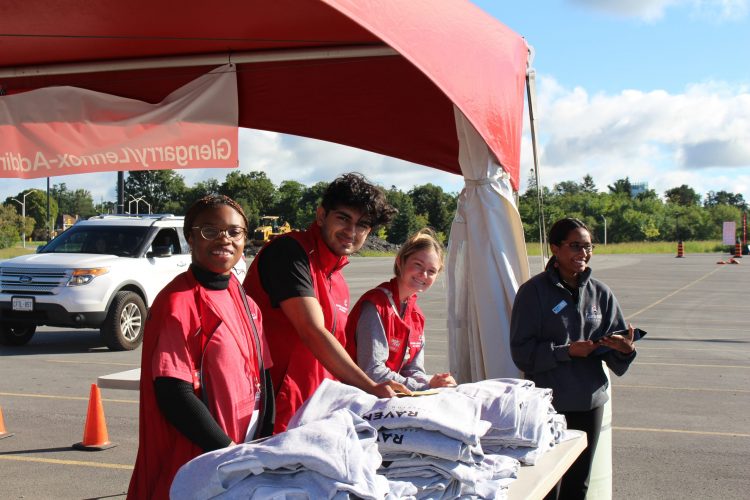 Four students standing under a tent