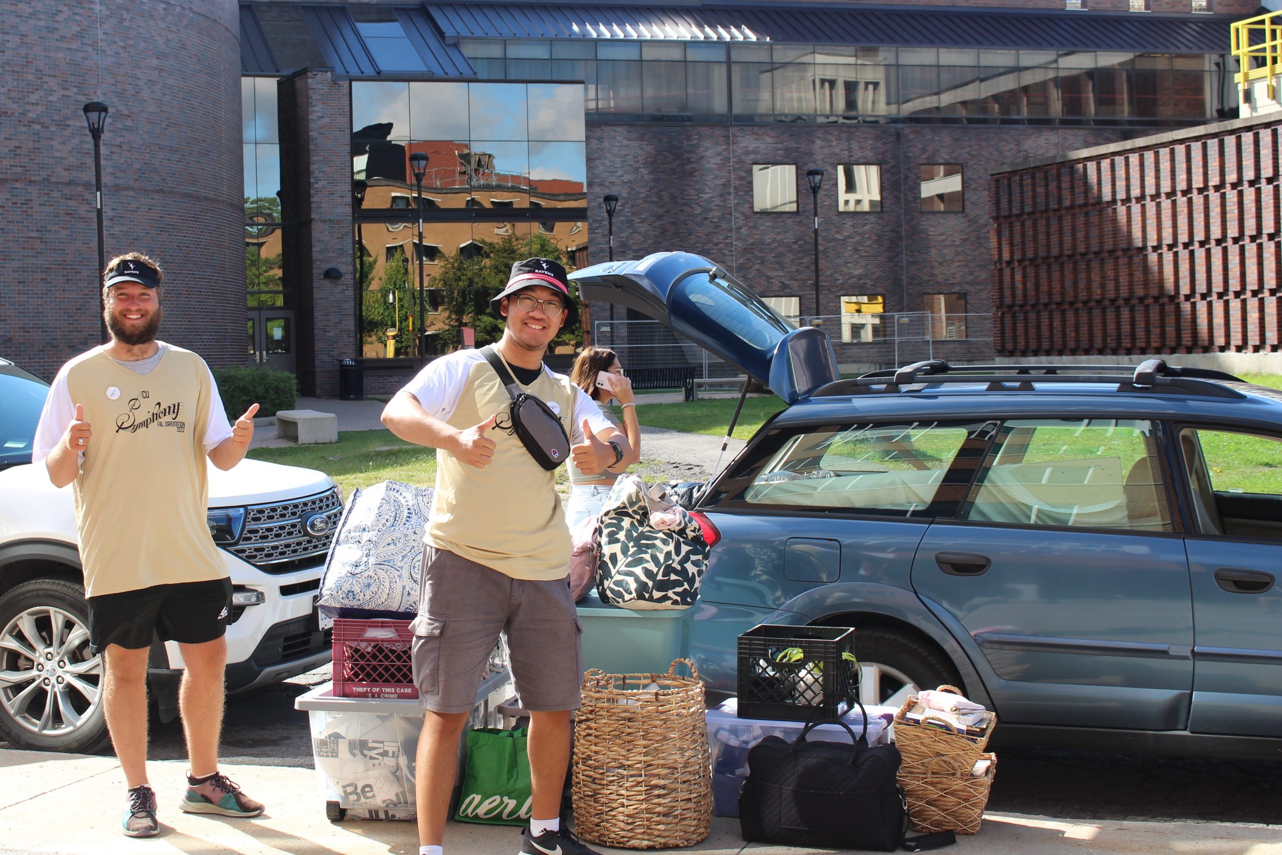 Two students standing in front of a car with their luggage