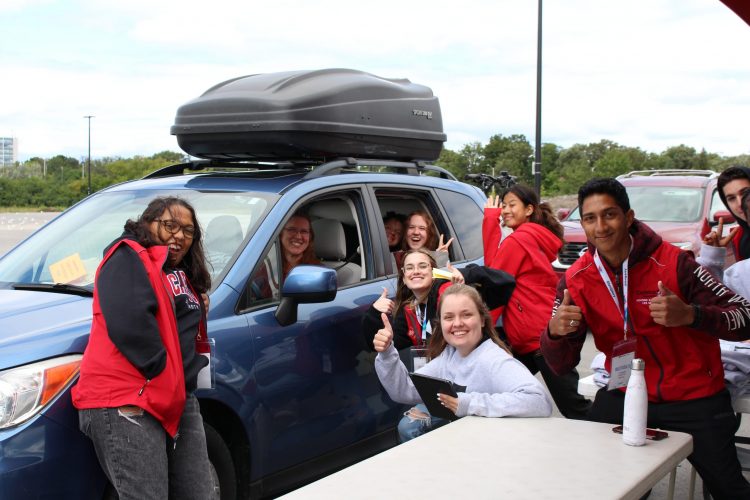 Students cheering at the new student in the car