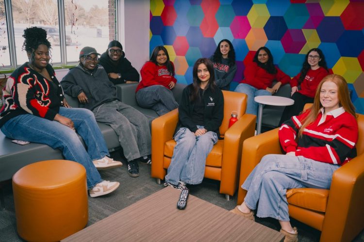 A group of Carleton students sit in a lounge, smiling.