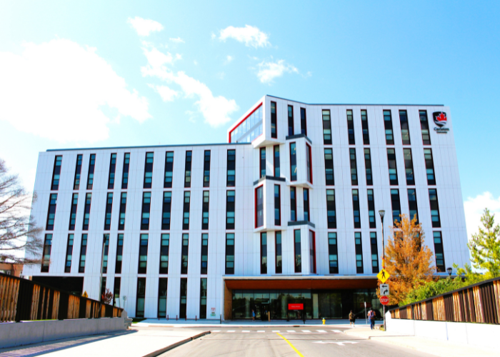 The exterior of Rideau House. A modern building with unique angular architecture, surrounded by snow-dusted trees and people.