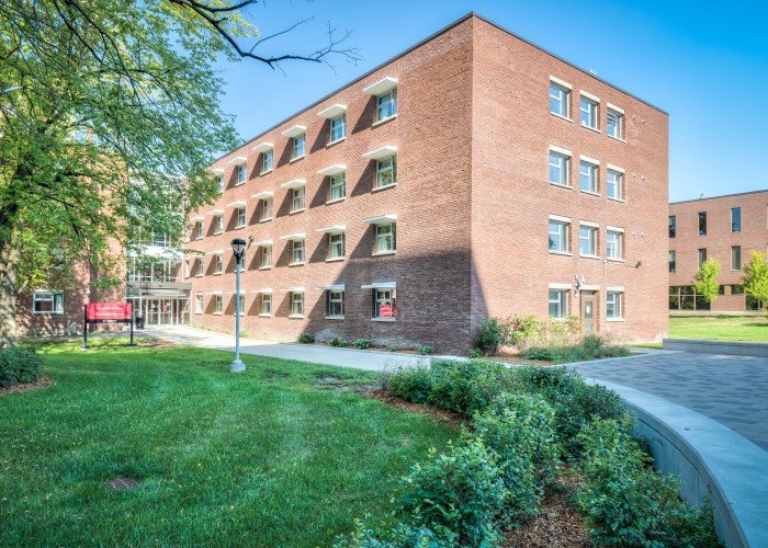 Russell House. A brick residence building with multiple windows surrounded by green grass and trees.