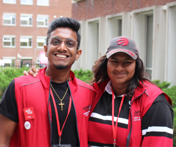 Two residence fellows smile while wearing red vests