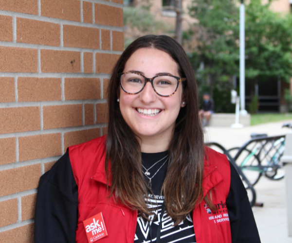 A member of residence staff smiles in front of a brick pillar