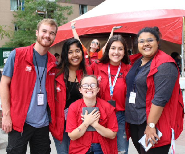 A group of residence staff pose for a photo in front of a red tent