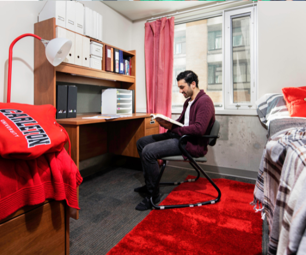 A residence student sits in his Carleton-themed room