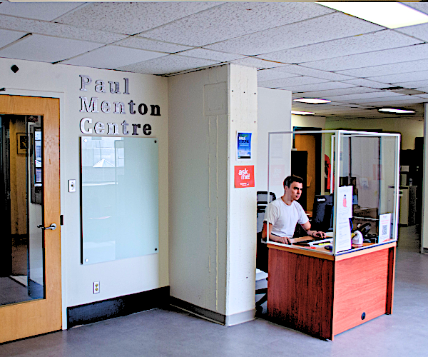 A man in a white shirt sits at a desk in the Paul Menton Centre